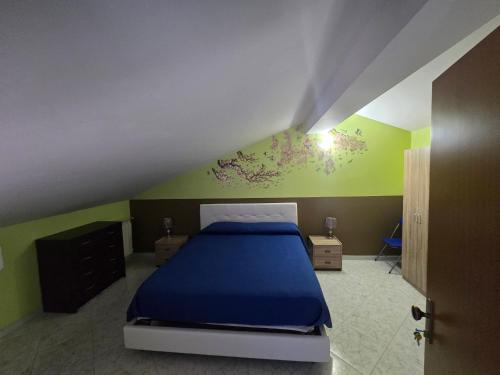 a bedroom with a blue bed and green walls at A Casa di Nonna in Riposto