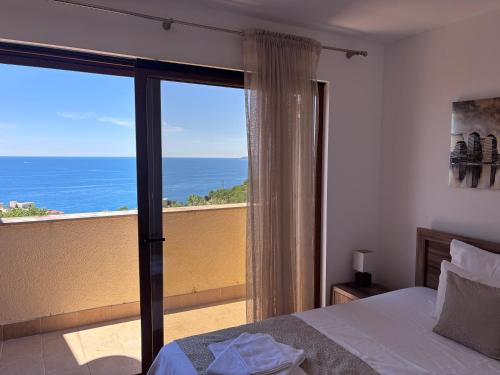 a bedroom with a view of the ocean from a balcony at Villa Rijeka Rezevici in Petrovac na Moru
