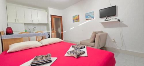 a room with a red bed with a chair and a television at Studio Rose in Gajac