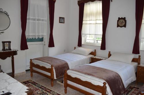 a bedroom with two beds and a clock on the wall at Old Bridge Guest House in Gjirokastër
