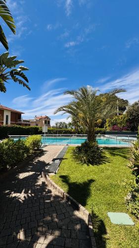a resort with a swimming pool and palm trees at Elegant Sea View Retreat in Historic Villa with Pool in Bordighera