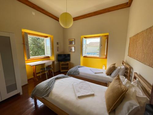 a bedroom with two beds and a desk and two windows at Casa da Abrunheira in Ramalhal