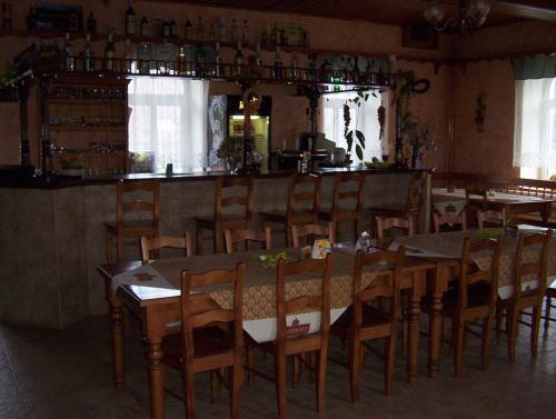 a dining room with tables and chairs and a bar at Penzion U červených vrat in Chudolazy