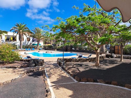 ein Resort-Schwimmbad mit Bäumen und Palmen in der Unterkunft Casa jablillo in Costa Teguise