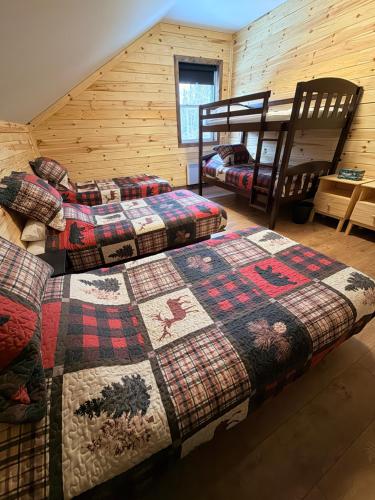 a bedroom with two beds and two bunk beds at Le Shack du Nord in Mont-Laurier