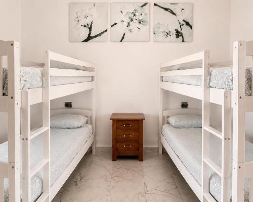 two white bunk beds in a room with a table at International Surf Camp ONLY SURF in Corralejo