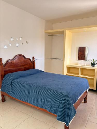 a bedroom with a bed with a blue blanket at La casa de los Faroles in Cuetzalán del Progreso