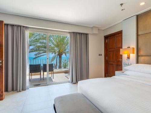 a bedroom with a bed and a view of the ocean at Mövenpick Hotel & Resort Al Bida'a in Kuwait