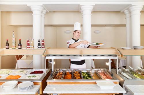 a chef preparing food in a restaurant kitchen at Hotel Westend in Mariánské Lázně