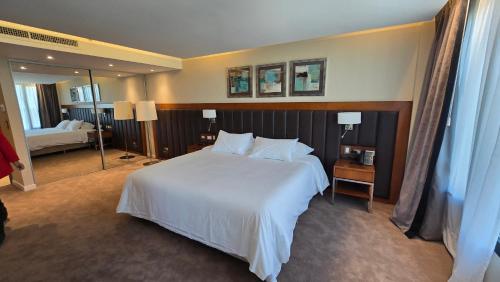 a bedroom with a large white bed and a mirror at Azahar Hotel & Spa in San Pedro