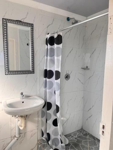 a bathroom with a black and white shower curtain and a sink at Sunset Guesthouse - Mthatha in Mthatha