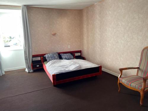 a bedroom with a bed and a chair and a window at Kerannie in Lanvollon