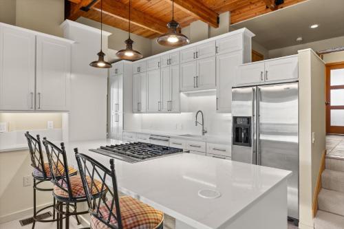 a kitchen with white cabinets and a kitchen island with chairs at 229 #35 by SkyRun Aspen in Snowmass Village