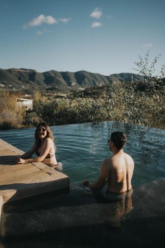 a man and a woman sitting in a swimming pool at Casa Misiones Glamping in Valle de Guadalupe