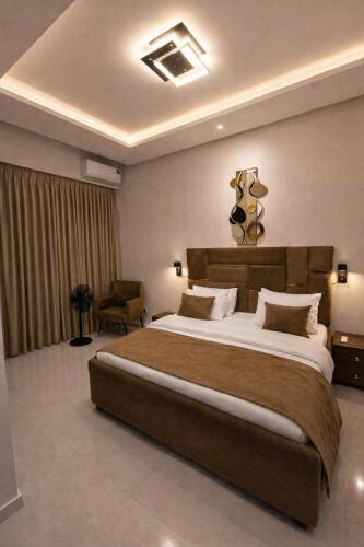 a bedroom with a large bed and a chair at DipNik Residence in Lagos