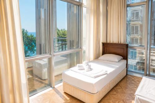 a bed in a room with large windows at Hotel Cameo in Kvariati