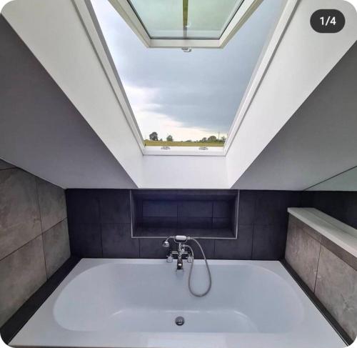 a bathroom with a large bath tub with a skylight at Chapel House Accommodation in Culgaith