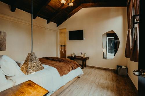 a bedroom with a bed and a table and a tv at Taura Wellness House - Boutique Stay & Experiences in Antigua Guatemala in Antigua Guatemala