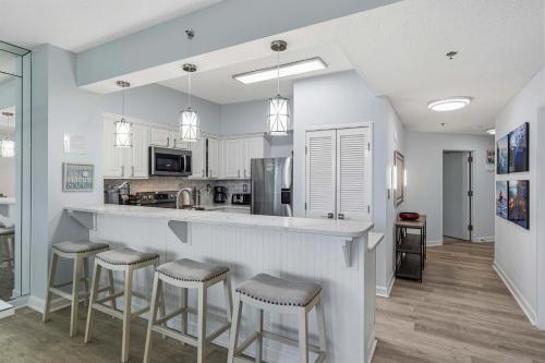 a kitchen with white cabinets and bar stools at TOPS'L Tides 0207 in Destin