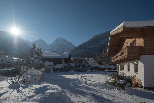 a building in the snow with the sun behind it at Haus Alpenblick Lofer in Lofer