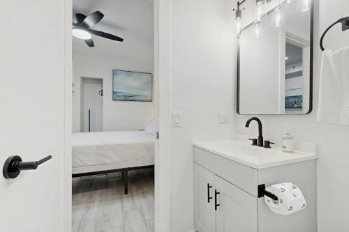 a white bathroom with a sink and a bed at Sunshine, Beach & Smiles on Ocean Drive in Miami Beach