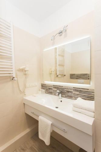 a white bathroom with a sink and a mirror at Hotel IOR in Poznań