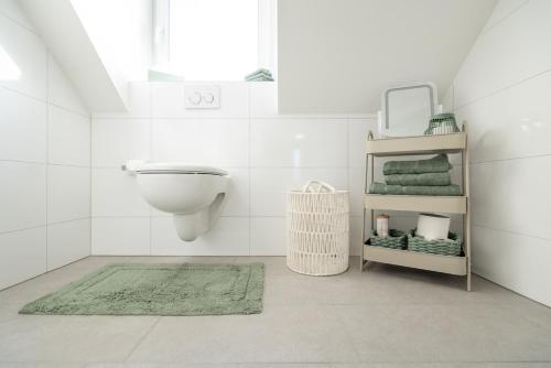 a bathroom with a toilet and a green rug at Sali Suite - Modern Attic Stay in Arbon