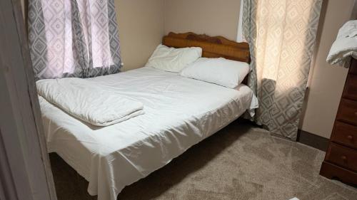 a small bed with white sheets and pillows at Plattsburgh Stay in Plattsburgh