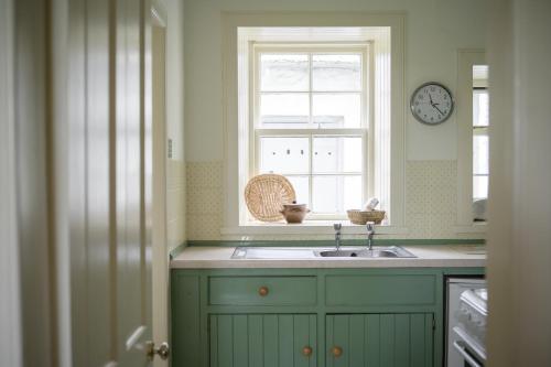 a kitchen with a sink and a window with a clock at Cardross Holiday Cottages in Arnprior