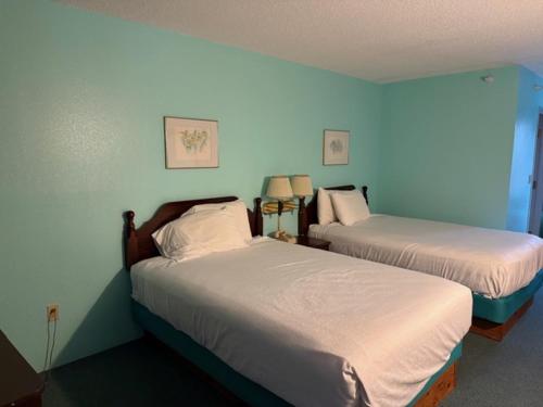two beds in a room with blue walls at UP NORTH HOTEL formerly Voyager Inn in Saint Ignace