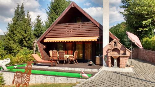 ein kleines Haus mit einem Tisch und Stühlen neben einem Pool in der Unterkunft Ferienhaus TSAVO in Wald-Michelbach