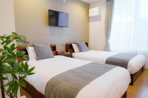 a hotel room with two beds and a flat screen tv at Solis Studio Miyako SeaSide in Miyako-jima