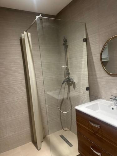 a shower with a glass door next to a sink at Joli appartement à Tamaris in Dar Bouazza