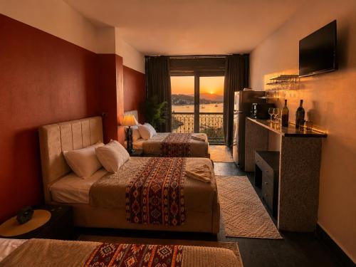 a hotel room with two beds and a balcony at Aswan sunrise in Aswan