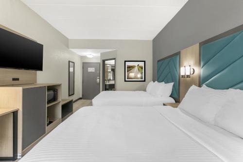 a hotel room with two beds and a flat screen tv at Best Western Eagles Inn in Morehead