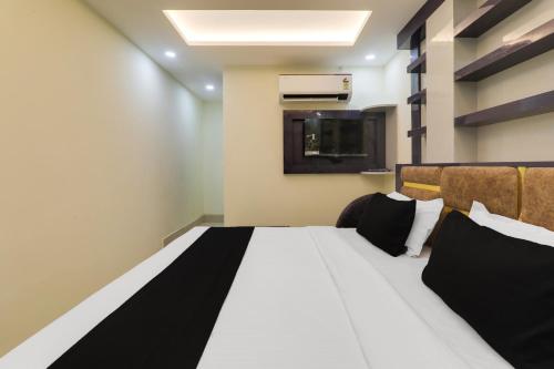 a bedroom with a large white bed with black pillows at HOTEL O PRAGATI in Gorakhpur