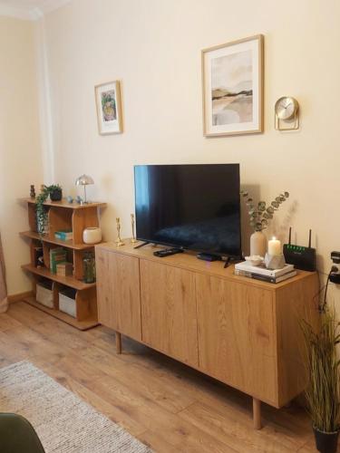 a living room with a flat screen tv on a wooden cabinet at The Velvet Stay in Tbilisi City