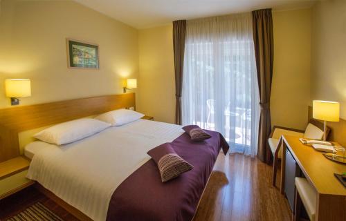 a hotel room with a large bed and a window at Hotel Villa Privileggio in Mošćenička Draga