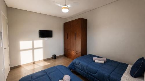 a living room with a blue couch and a tv at Casa de Hóspedes Jaú in Jaú