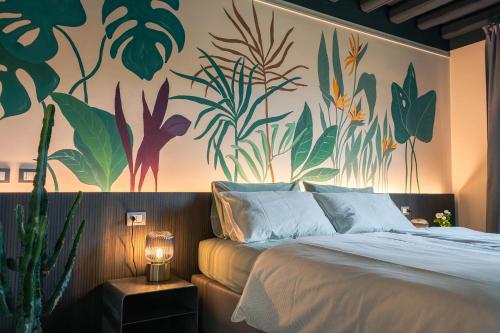a bedroom with a bed with a painting of plants on the wall at Dimora al Glicine in Sernaglia della Battaglia