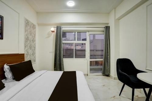 a bedroom with a bed and a table and a window at Super Townhouse Rosens hotel in Noida