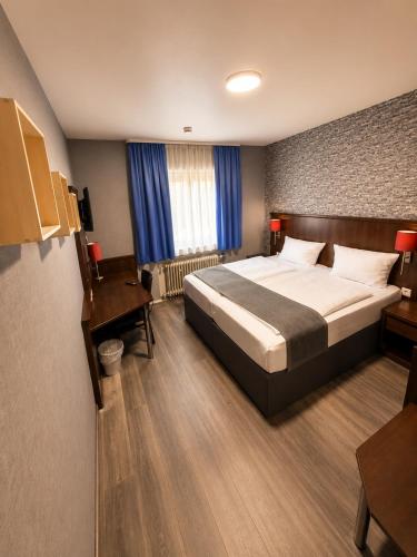 a hotel room with a bed and a desk and a bed sidx sidx sidx sidx at Parkhotel Lindenhof - KOSTENLOSE PARKPLÄTZE in Offenbach
