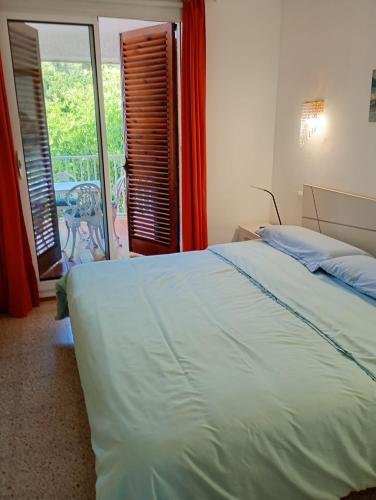 a bedroom with a white bed and a balcony at Apartamentos Escorpion Tossa de Mar in Tossa de Mar