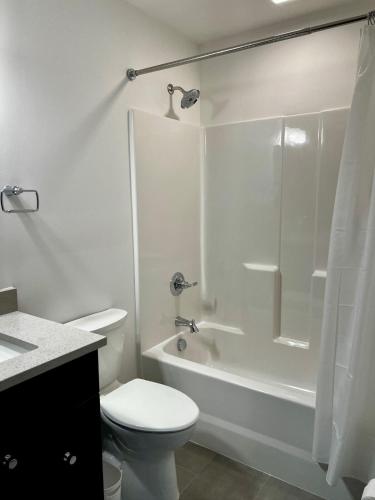 a white bathroom with a toilet and a shower at Brick & Bed Riverfront Lofts, T 202 in Saint Louis