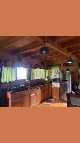 a kitchen with wooden cabinets and a stainless steel refrigerator at Cabaña Facovi in Empalme