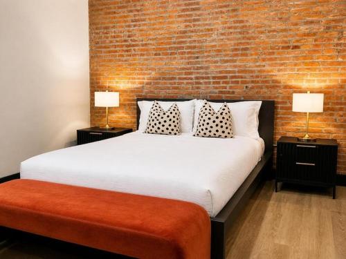 a bedroom with a large bed with a brick wall at Brick & Bed Riverfront Lofts, T 202 in Saint Louis