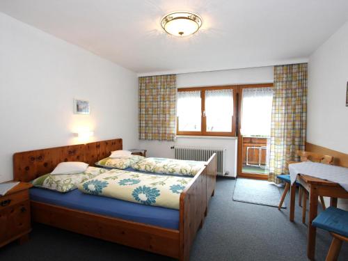 a bedroom with a bed and a table and windows at Veronika in Fulpmes