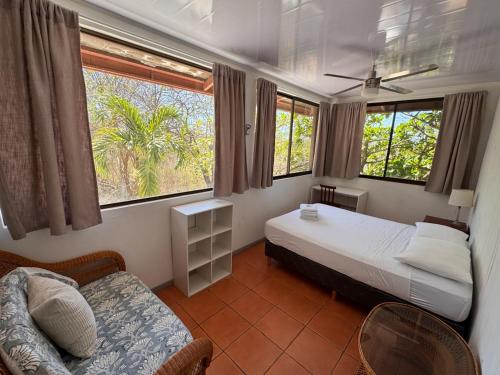a bedroom with two beds and a chair and two windows at Blue Dream Kite Boarding Resort Costa Rica in Puerto Soley