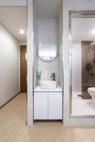 a white bathroom with a sink and a mirror at lazy tiger hotel in Seoul