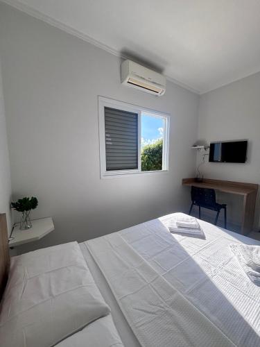 a white bedroom with a bed and a window at Spazio Italian Lofts in Paulínia